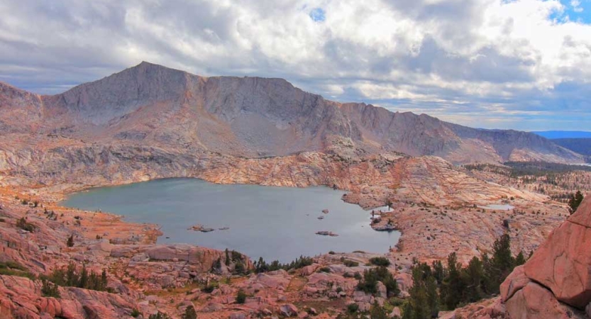 An alpine lake is framed by red mountains of the high sierra